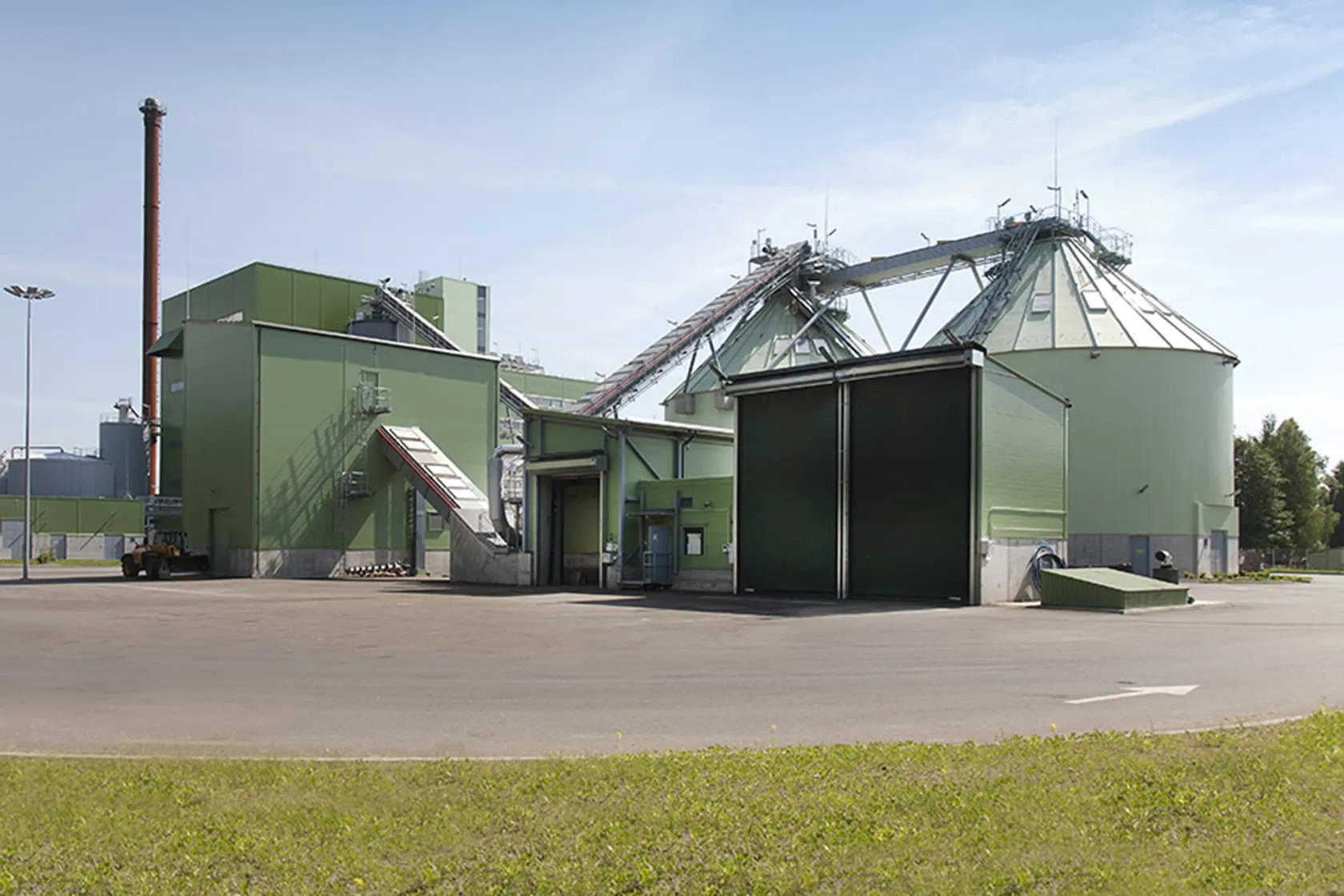 Green biomass power plant against a clear blue sky